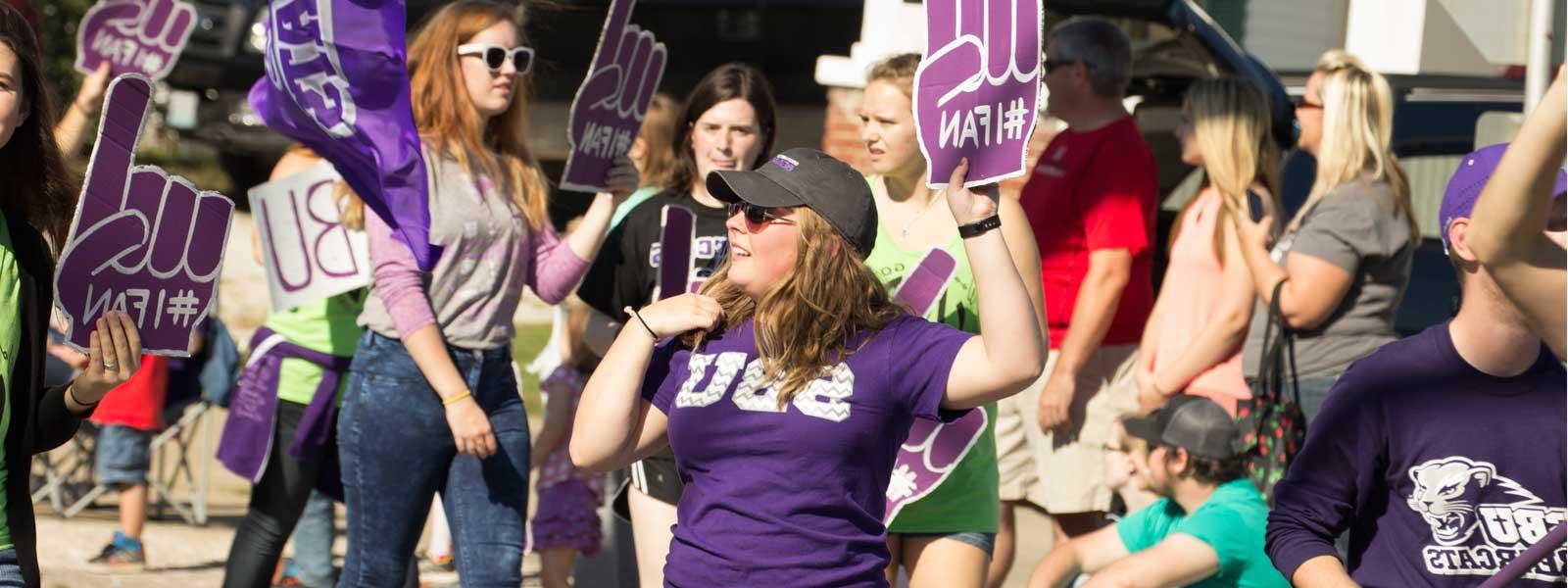 students with foam fingers marching in Homecoming parade