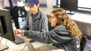 students looking at laptop screens while sitting around conference table