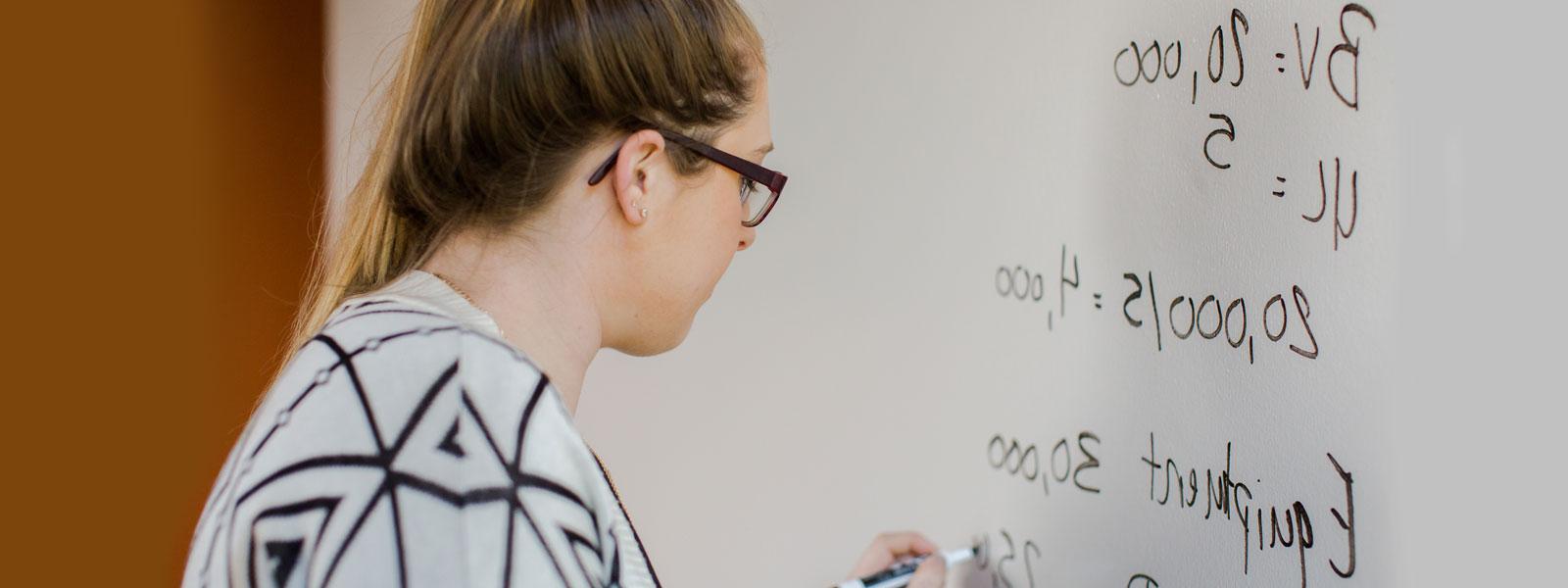 student works on accounting problem on whiteboard