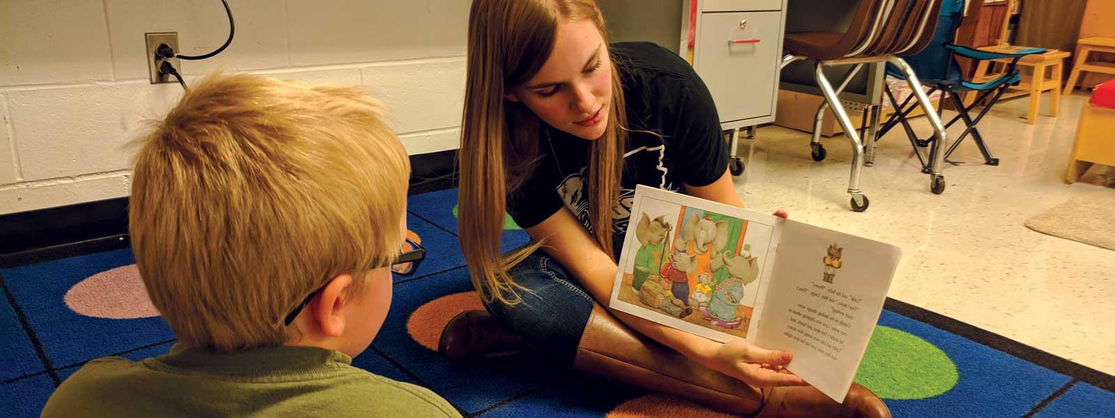 female college student reads book to young boy